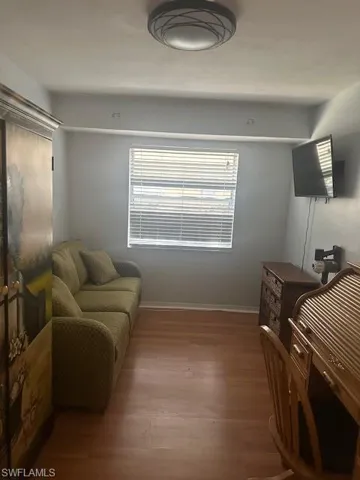 Den featuring queen size sofa sleeper, wardrobe, roll top desk, TV, wood finished floors