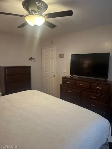 Bedroom featuring large screen TV, ample storage dressers, ceiling fan