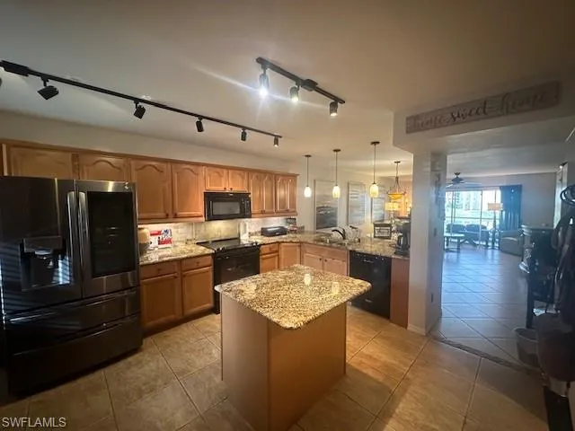 Spacious open kitchen with granite countertops, decorative backsplash, modern appliances, and island