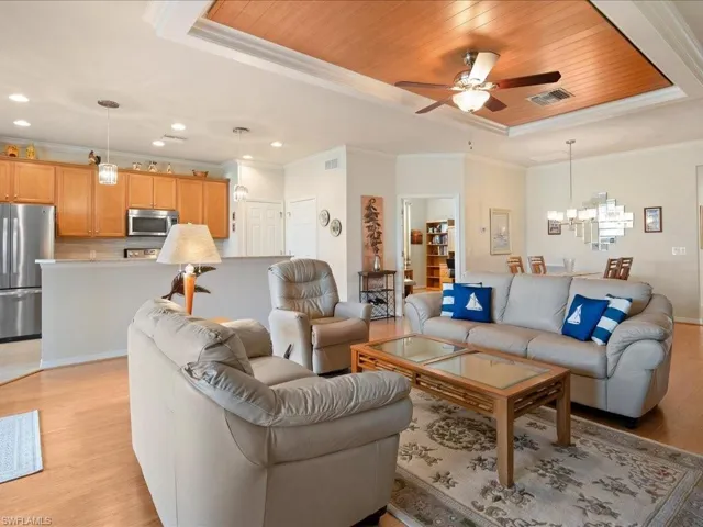 Living room with ceiling fan with crown molding, and wood ceiling