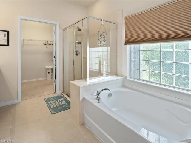 Bathroom with shower with separate bathtub and tile flooring