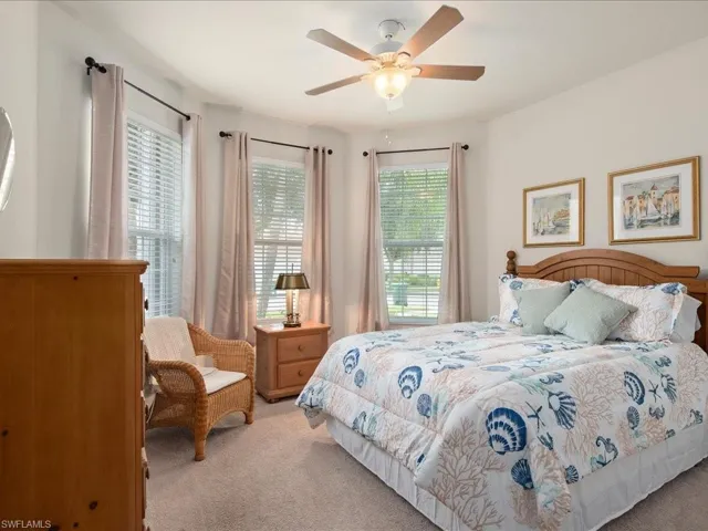 Carpeted bedroom with ceiling fan and multiple windows