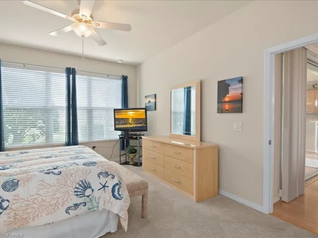 Bedroom with multiple windows, light colored carpet, and ceiling fan