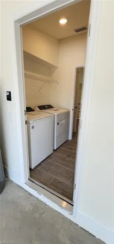 Laundry area with wood finish floors, washer and dryer, and recessed lighting