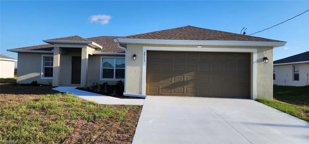 Single story home featuring stucco siding, roof with shingles, concrete driveway, and a garage
