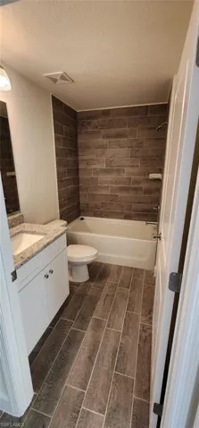 Bathroom featuring vanity, wood finish floors, shower / tub combination, and a textured ceiling
