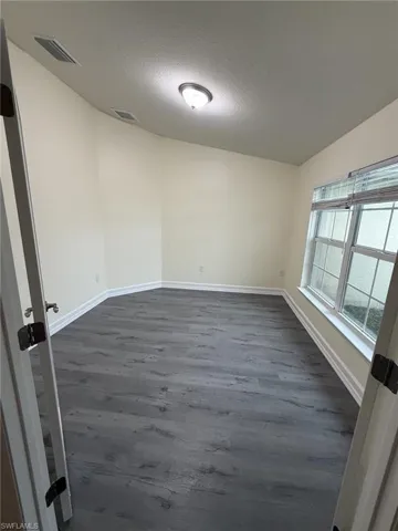 Empty room featuring dark wood-style flooring and a textured ceiling
