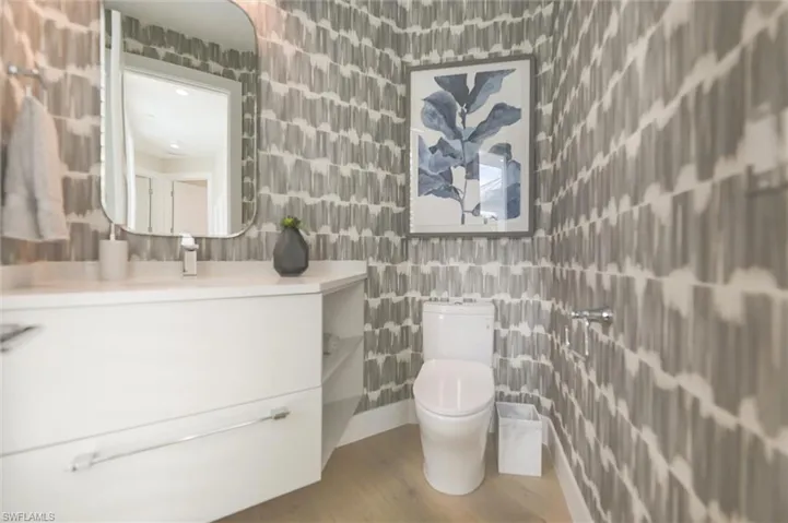 Bathroom with tile walls, hardwood / wood-style floors, toilet, and vanity