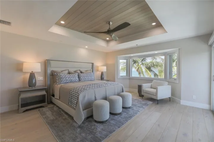Bedroom with a tray ceiling, wood ceiling, ceiling fan, and light hardwood / wood-style flooring