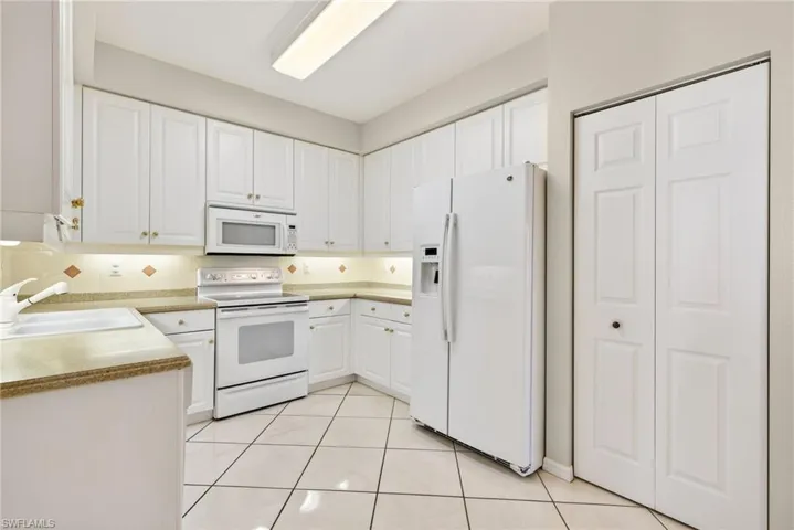 VIRTUALLY REFRESHED WITH A NEUTRAL PALETTE!  featuring white appliances, white cabinets, and light tile patterned flooring