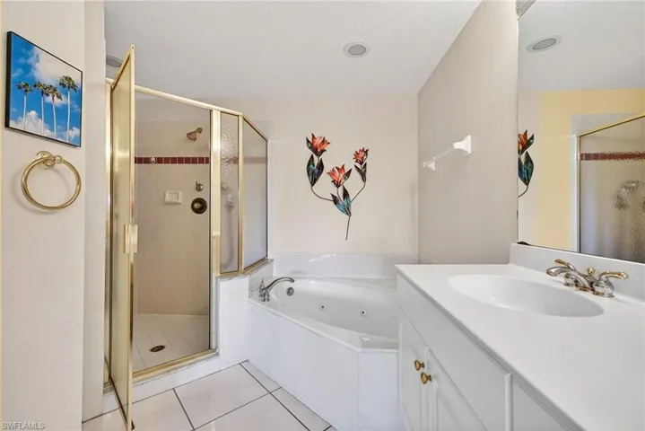 VIRTUALLY REFRESHED WITH A NEUTRAL PALETTE!  with a whirlpool tub, a stall shower, vanity, and light tile patterned flooring
