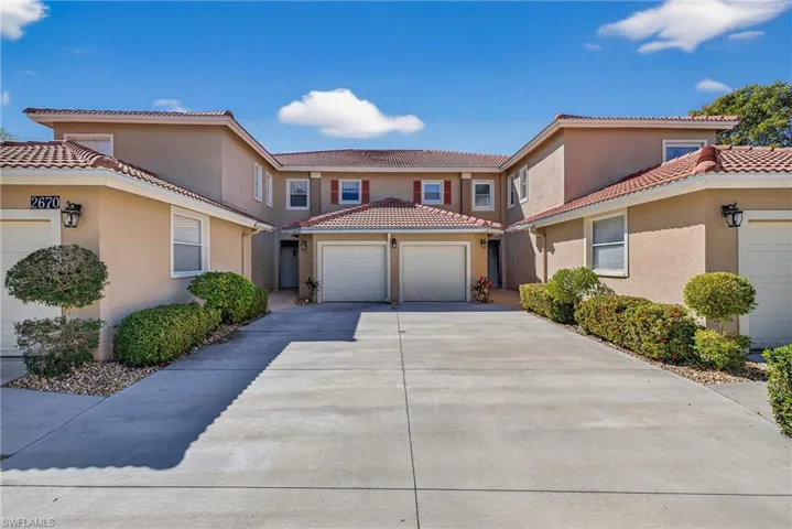 Carriage home with long driveway, attached garage, stucco siding, and a newer tile roof