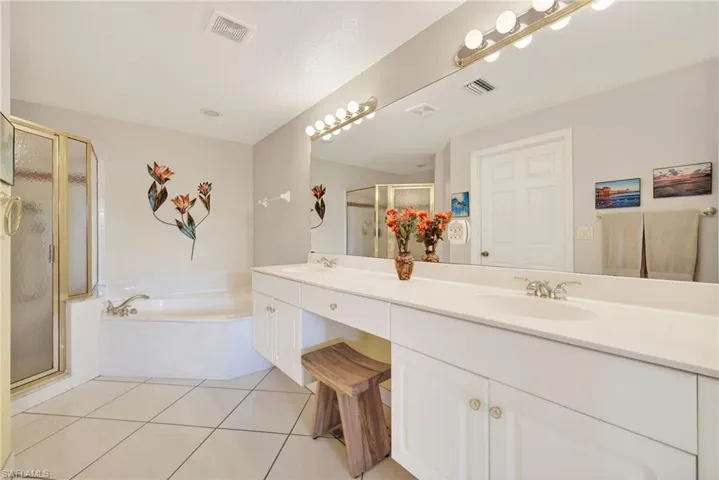 VIRTUALLY REFRESHED WITH A NEUTRAL PALETTE!  bath featuring a stall shower, a bath, double vanity, and light tile patterned floors