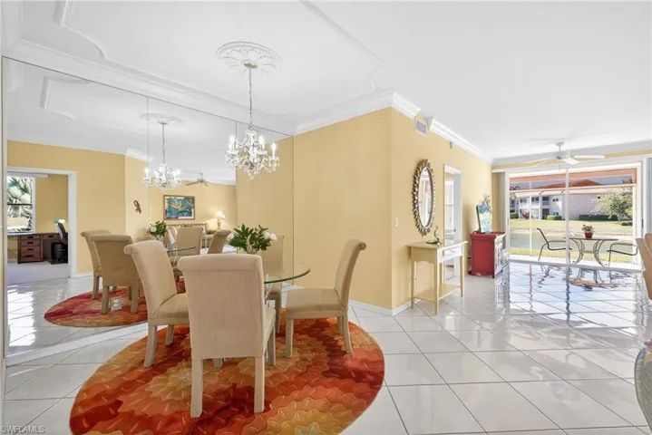 Dining area with crown molding, chandelier, custom mirror, ceiling fan, white tile diagonal flooring,and double door sliders to the lanai