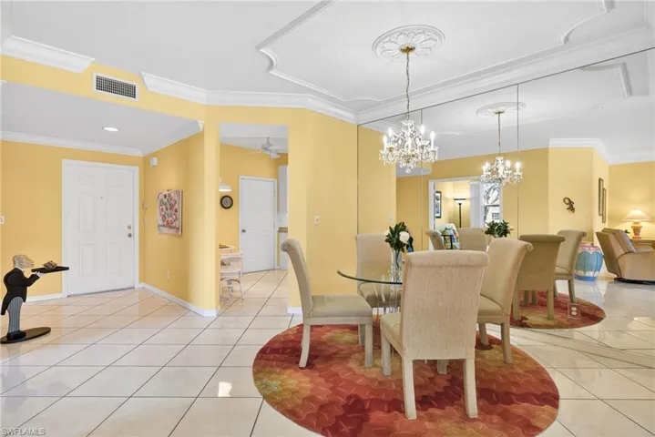 Dining area with crown molding, chandelier, custom mirror, ceiling fan, and white tile diagonal flooring