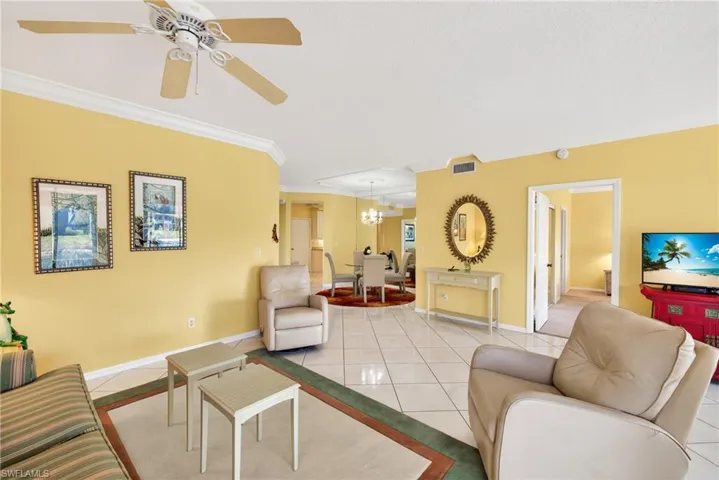 Great room with crown molding, diagonal white ceramic tile flooring, and ceiling fan