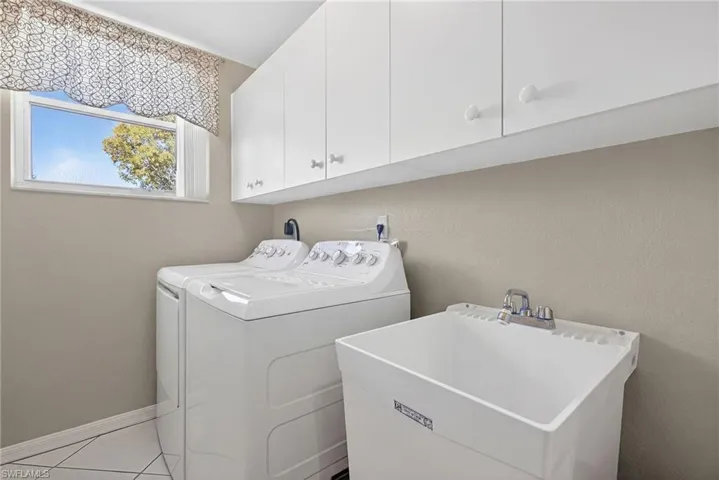 VIRTUALLY REFRESHED WITH A NEUTRAL PALETTE!  room featuring cabinet space, washing machine and clothes dryer, and light tile patterned floors