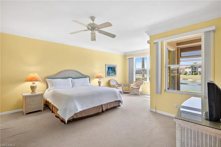 Owners suite bedroom featuring crown molding, carpet floors, ceiling fan, and large sitting area with sweeping lake views