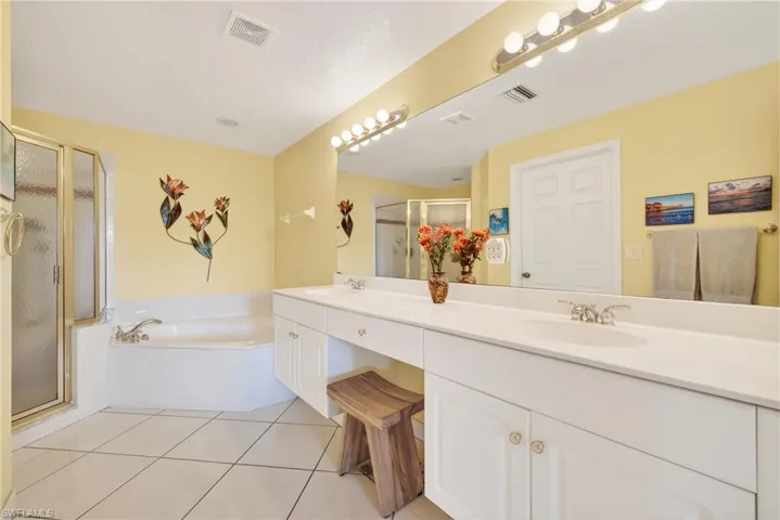 Full bath with a soaking tub, large shower, double vanity with sitting area, and light tile patterned floors