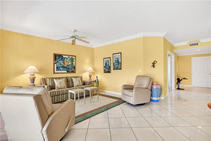 Great room with crown molding, diagonal white ceramic tile flooring, and ceiling fan