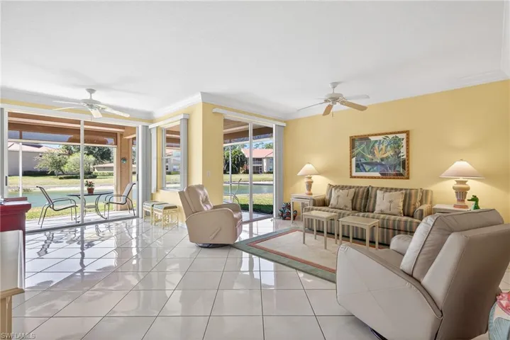 Great room with ceiling fans, crown molding, and upgraded diagonal white porcelain tile