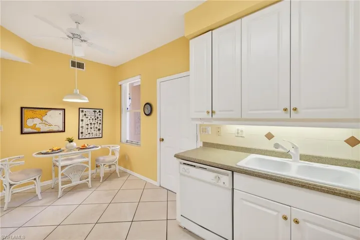 Kitchen with breakfast nook, white cabinets, dishwasher, and white tile patterned floors