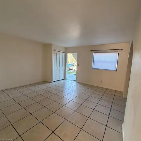Empty room with light tile patterned flooring and arched walkways