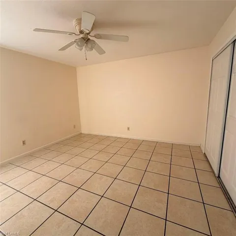 Empty room with light tile patterned floors and ceiling fan