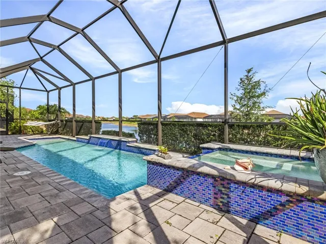 View of pool featuring a patio, a lanai, and a pool with connected hot tub