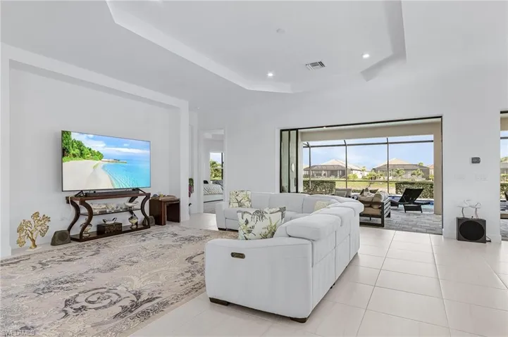 Living room featuring a tray ceiling, light tile patterned floors, and recessed lighting