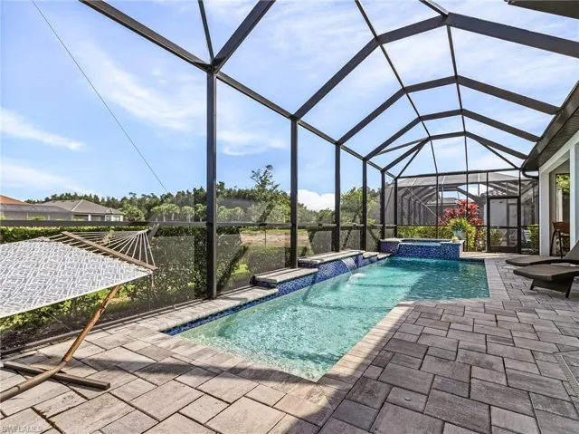 View of swimming pool featuring a patio area, a pool with connected hot tub, and a lanai