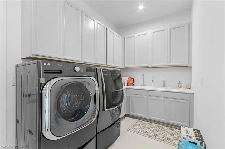 Washroom with independent washer and dryer, cabinet space, and light tile patterned flooring
