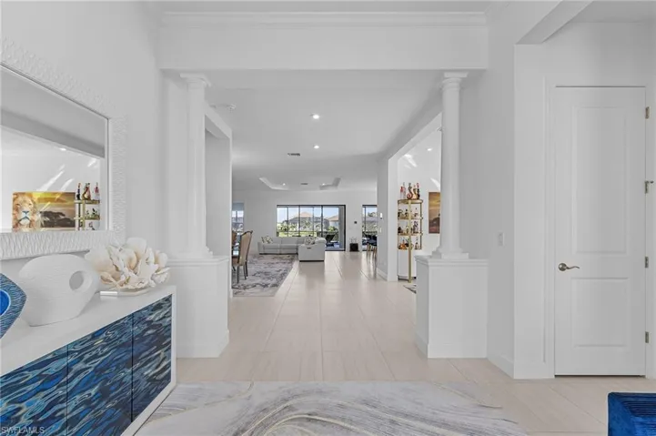 Hallway with ornate columns, tile patterned flooring, and recessed lighting