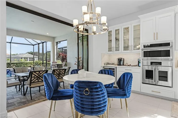 Dining room with a chandelier, light tile patterned floors, a sunroom, and beverage cooler