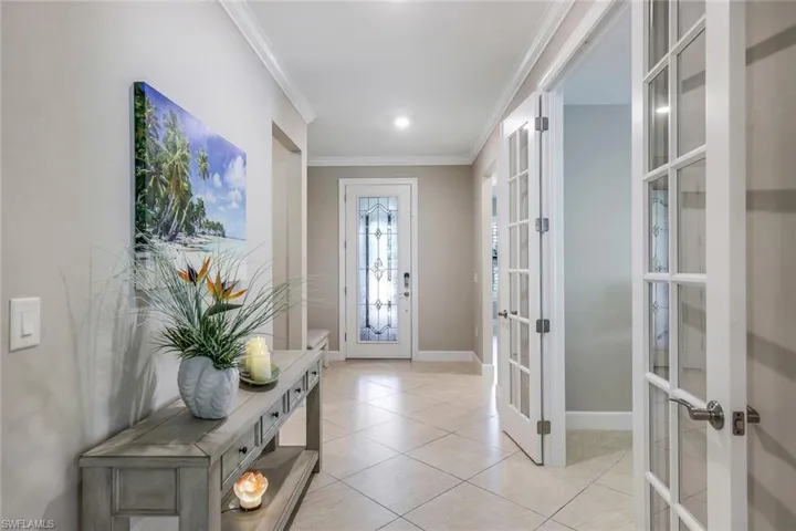 Tiled entryway featuring ornamental molding and french doors
