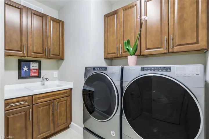 Laundry area with sink, washer and dryer, cabinets, and light tile floors