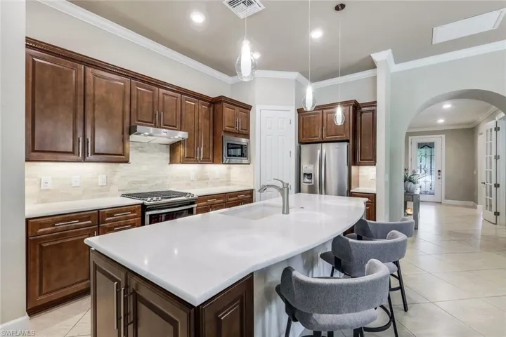 Kitchen featuring appliances with stainless steel finishes, sink, hanging light fixtures, and an island with sink