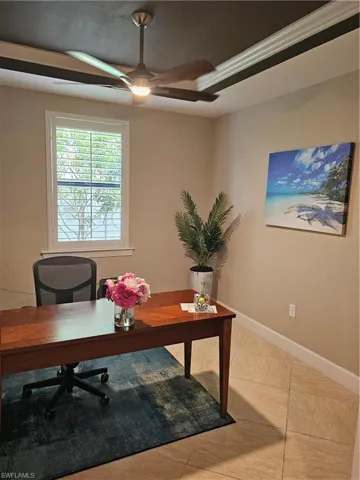 Tiled office featuring ornamental molding, ceiling fan, and a raised ceiling