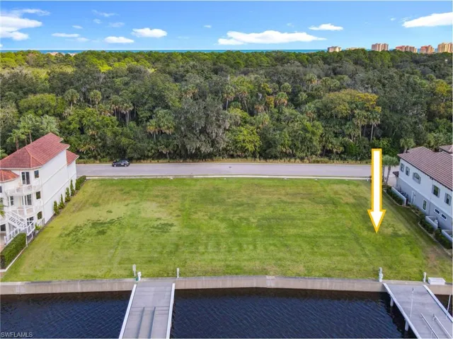Expansive waterfront lot featuring a green lawn, private dock, and concrete seawall