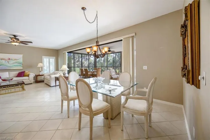 Dining space featuring ceiling fan with notable chandelier and light tile patterned flooring