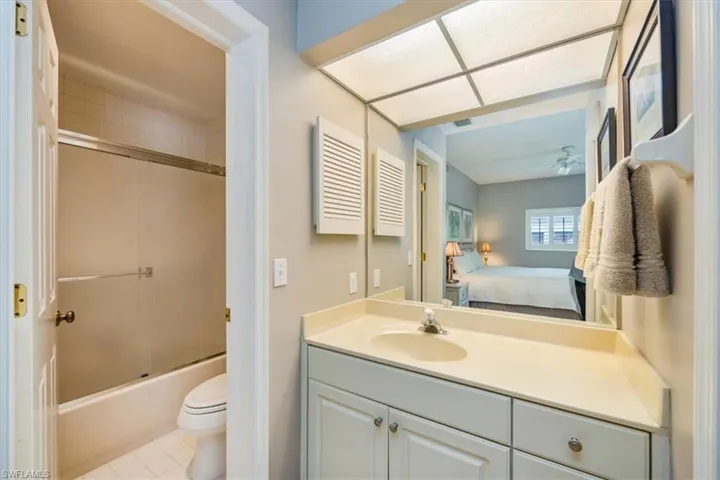 Full bathroom with tile patterned flooring, vanity, toilet, and bath / shower combo with glass door