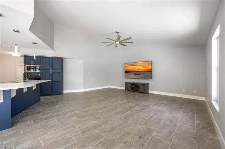 Unfurnished living room featuring a ceiling fan and high vaulted ceiling
