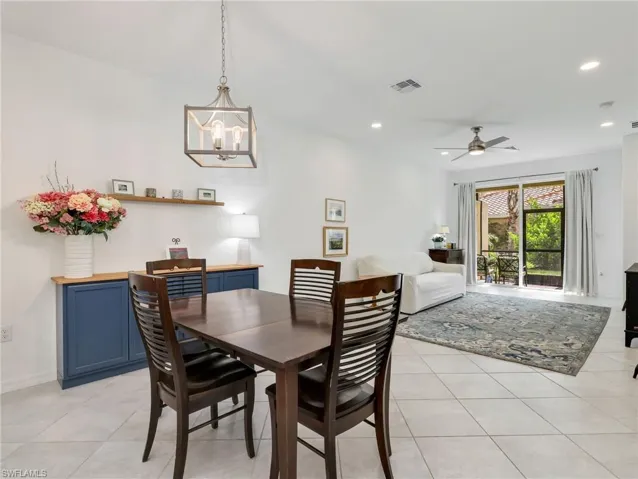 Open-concept living space featuring neutral tile flooring, a dining area with a wood-finish table, and a built-in blue cabinetry buffet with a wood countertop