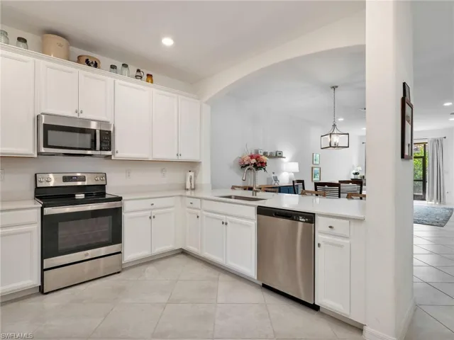 Modern kitchen featuring white cabinetry, light-toned countertops, stainless steel appliances, and large format tile flooring