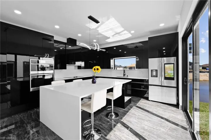 Kitchen featuring dark cabinets, appliances with stainless steel finishes, dark marble finish flooring, modern cabinets, and recessed lighting