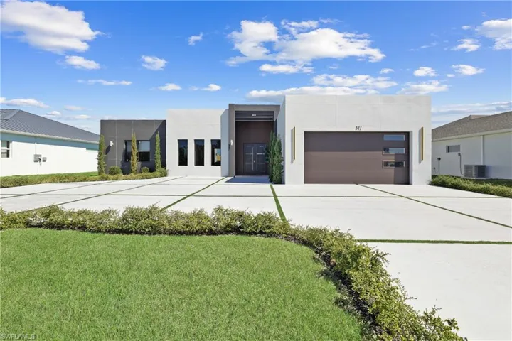 Modern home with driveway, an attached garage, cooling unit, and stucco siding