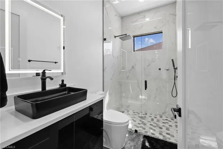 Bathroom featuring toilet, a marble finish shower, vanity, and marble finish flooring
