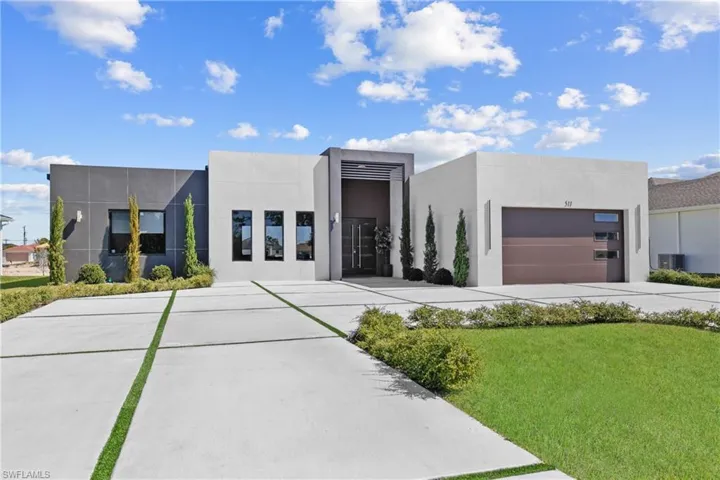 Contemporary home featuring concrete driveway, stucco siding, central air condition unit, and a front lawn