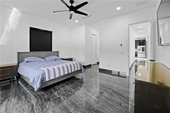 Bedroom with recessed lighting, a ceiling fan, and stainless steel refrigerator with ice dispenser