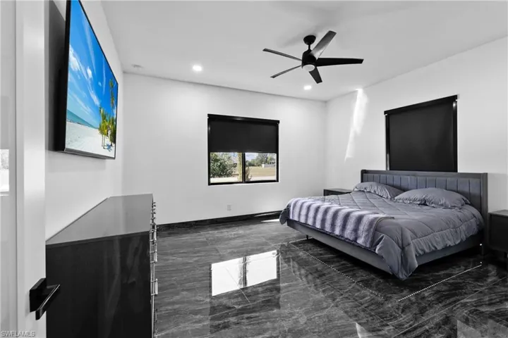 Bedroom with dark marble finish flooring, recessed lighting, and ceiling fan